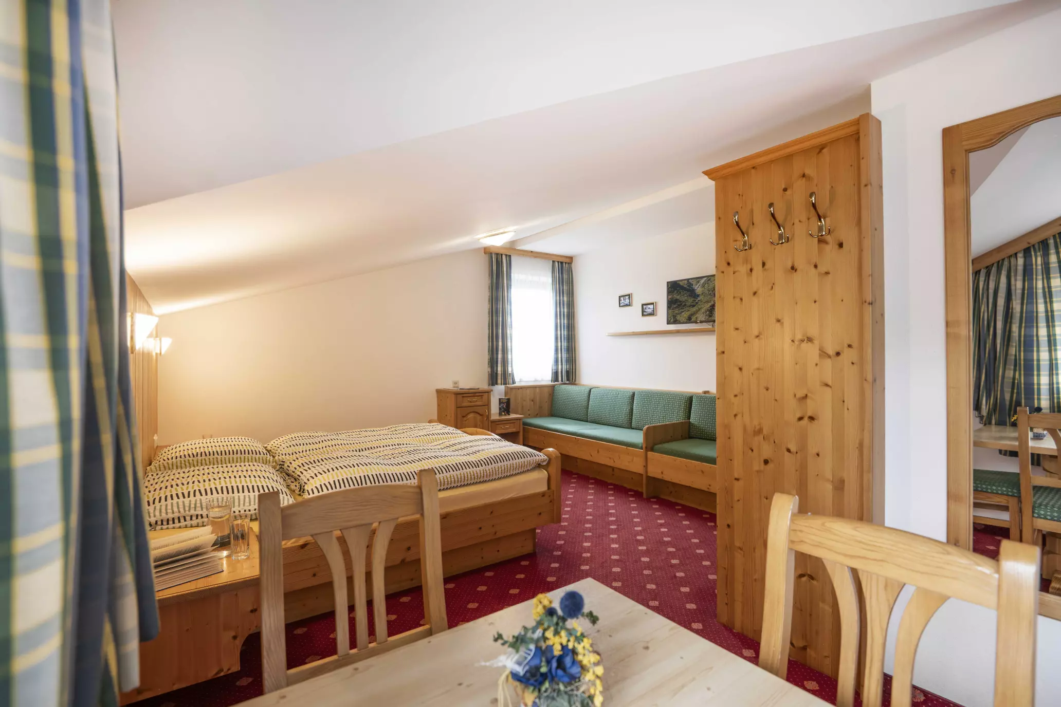 Zimmer mit Doppelbett, Sitzbank und Esstisch aus Holz