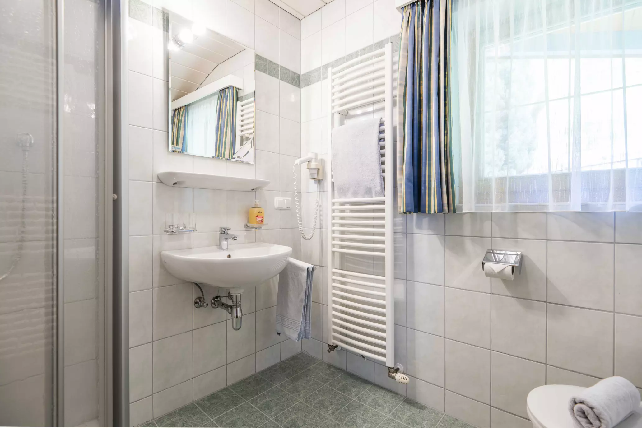 Helles Badezimmer mit Dusche, Waschbecken, Haarfön und WC