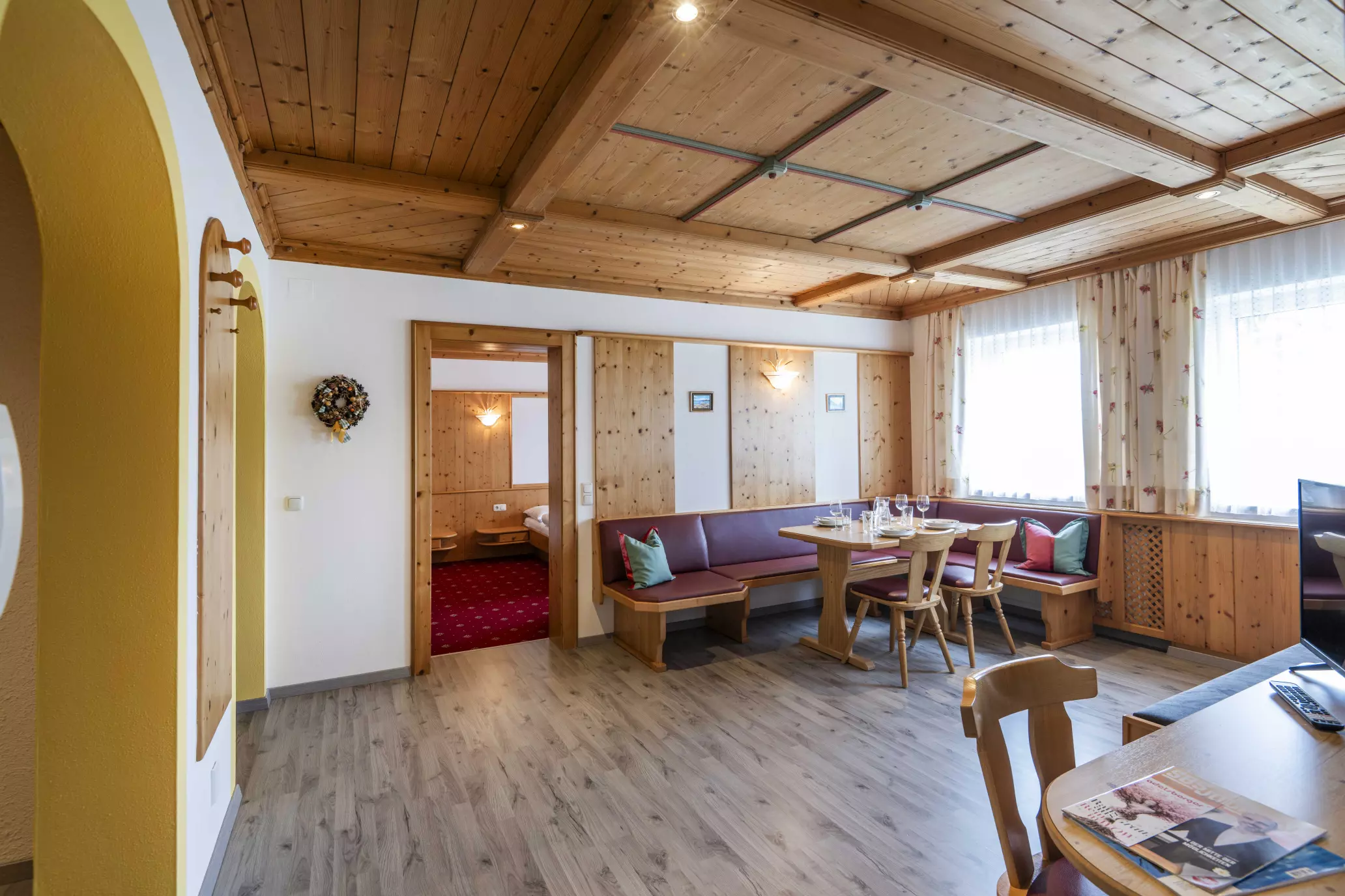 Wohnstube mit Eckbank, Esstisch und Durchgang zum Schlafzimmer
