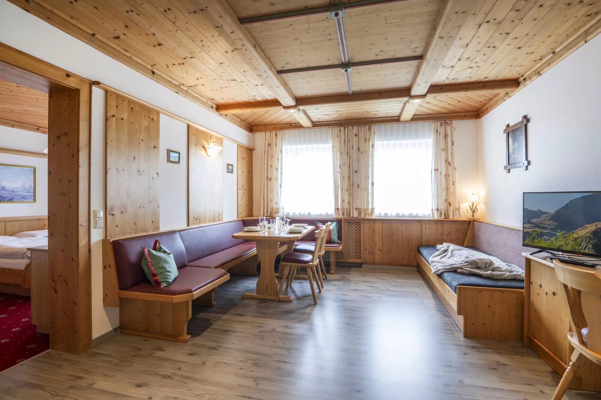 Helle Wohnstube mit gedecktem Tisch, Eckbank und SAT-TV