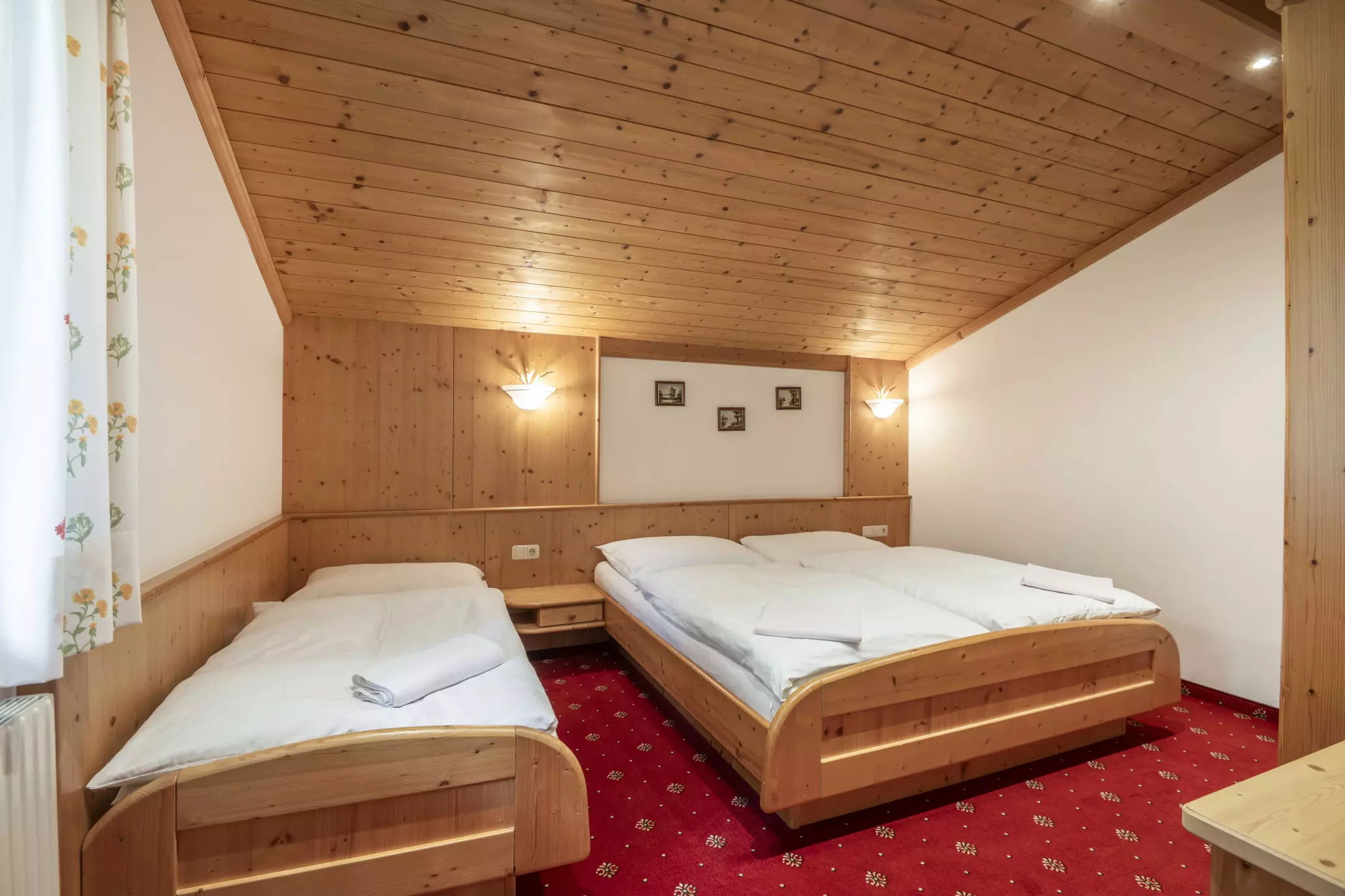 Schlafzimmer unter Holzdecke mit Doppelbett und Einzelbett