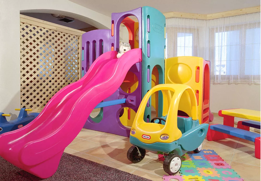 Buntes Spielzimmer mit Rutsche, Spielturm, Rutschauto und Kindertisch